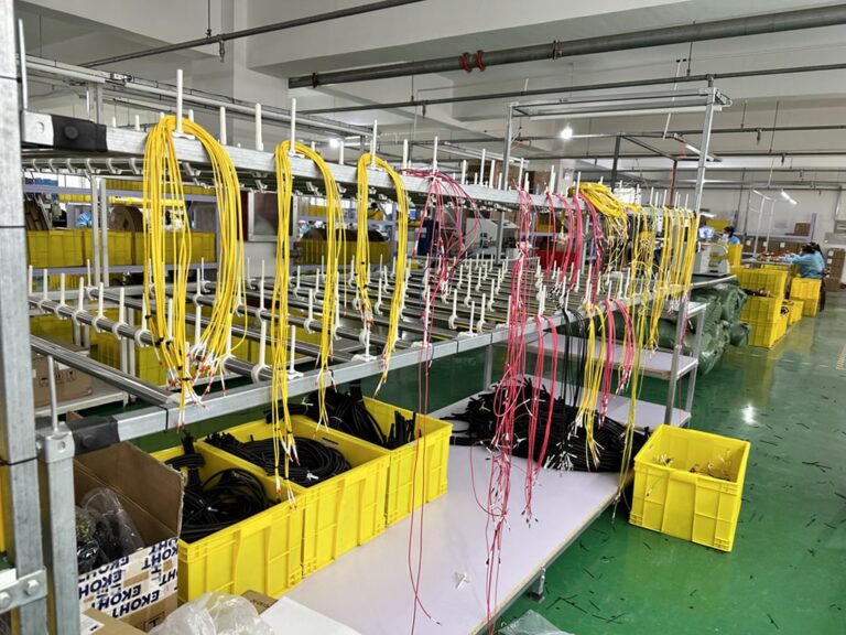 Organized racks of yellow and red wire harnesses in a manufacturing facility.